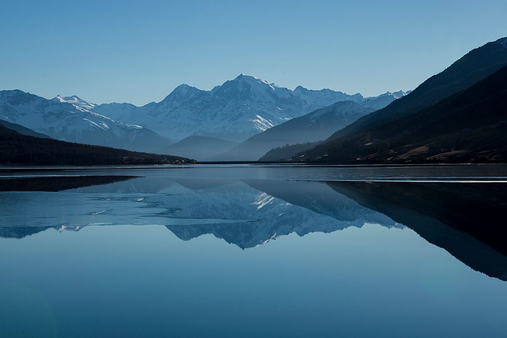 Calm mountain lake mirroring snow-capped peaks